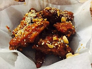 Deep Fried Chicken Wings with Spicy Sauce top with crushed peanuts and sesame